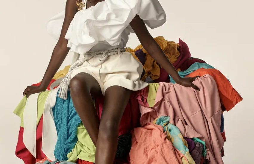 Vogue model seating on a pile of clothes for sustainable campaign